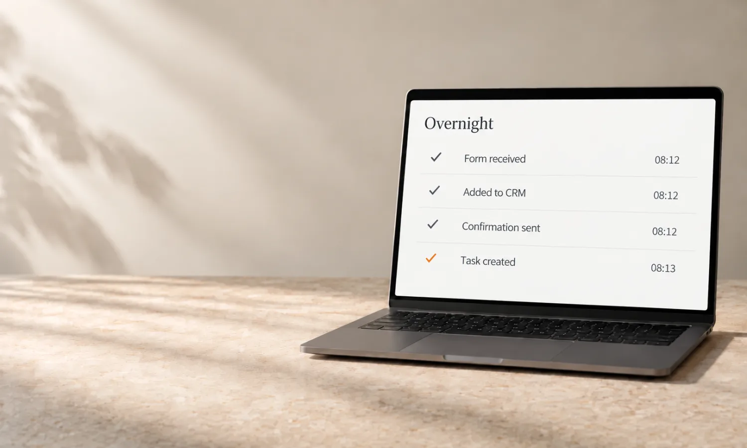 A laptop on cream stone; on screen an overnight activity list with four completed steps, the final tick in orange.