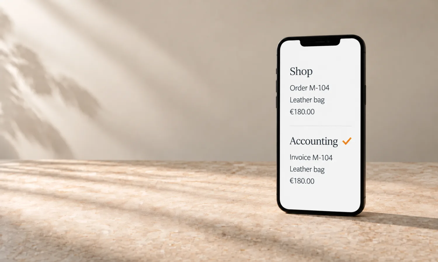 Smartphone auf cremefarbenem Stein; auf dem Bildschirm dieselbe Bestellung im Shop und in der Buchhaltung, getrennt durch eine schlichte Linie.